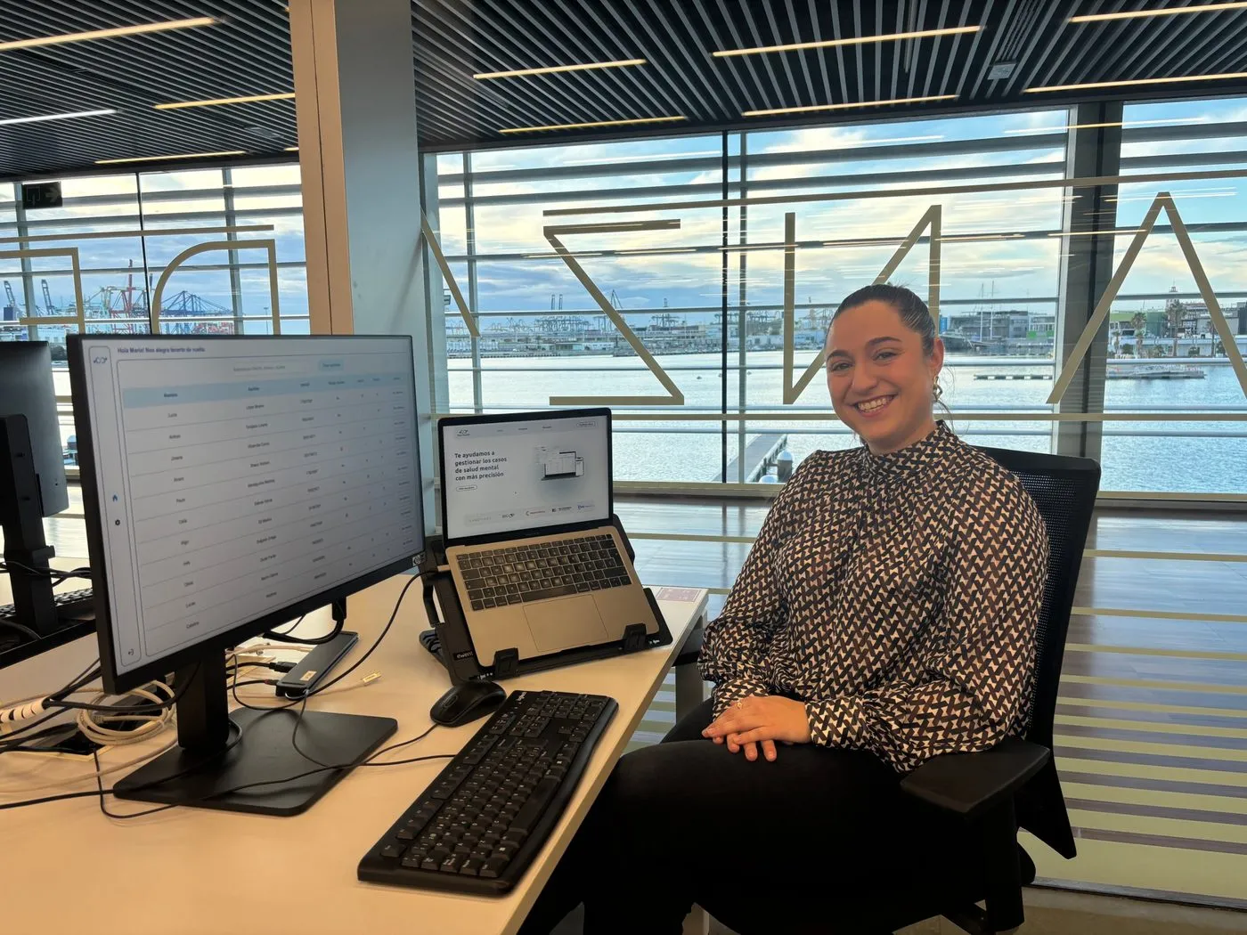 Eneka en su puesto de trabajo, con la plataforma de Nexi Health en pantalla y el puerto de fondo